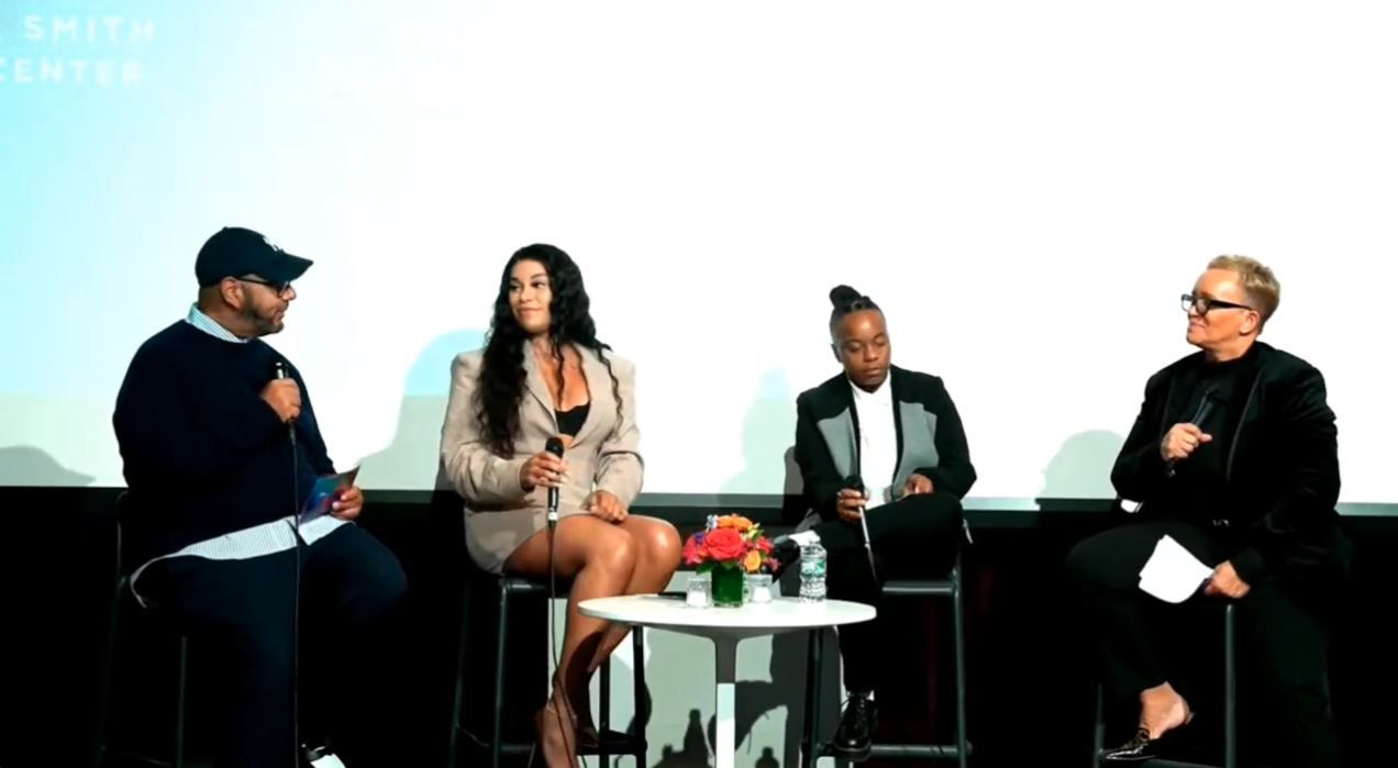 four people sit on stools on a stage talking